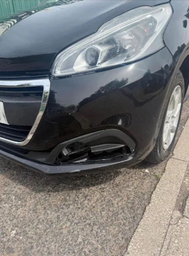 Condition photograph showing damage around the lower front bumper trim of the Peugeot 208