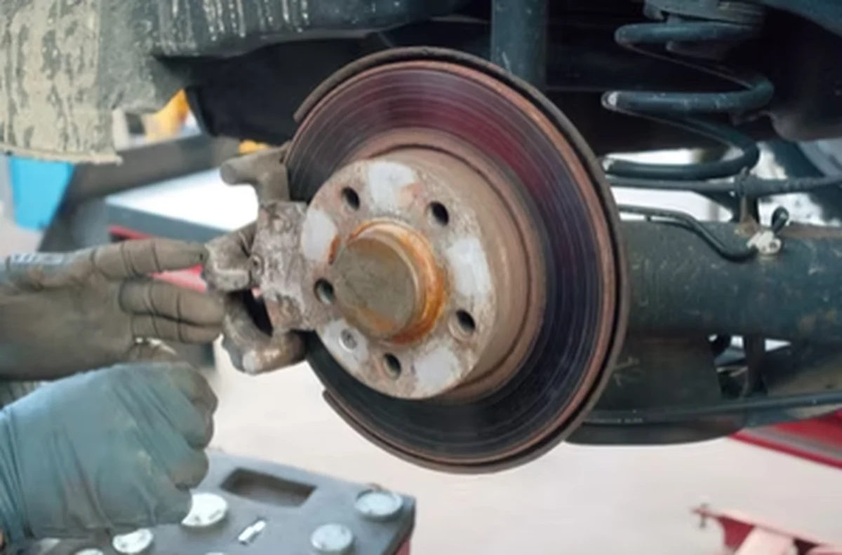 Mobile mechanic carrying out brake system repair on a brake disc and caliper