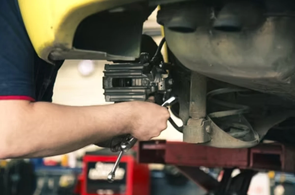Mechanic carrying out an engine oil and oil filter change beneath a vehicle