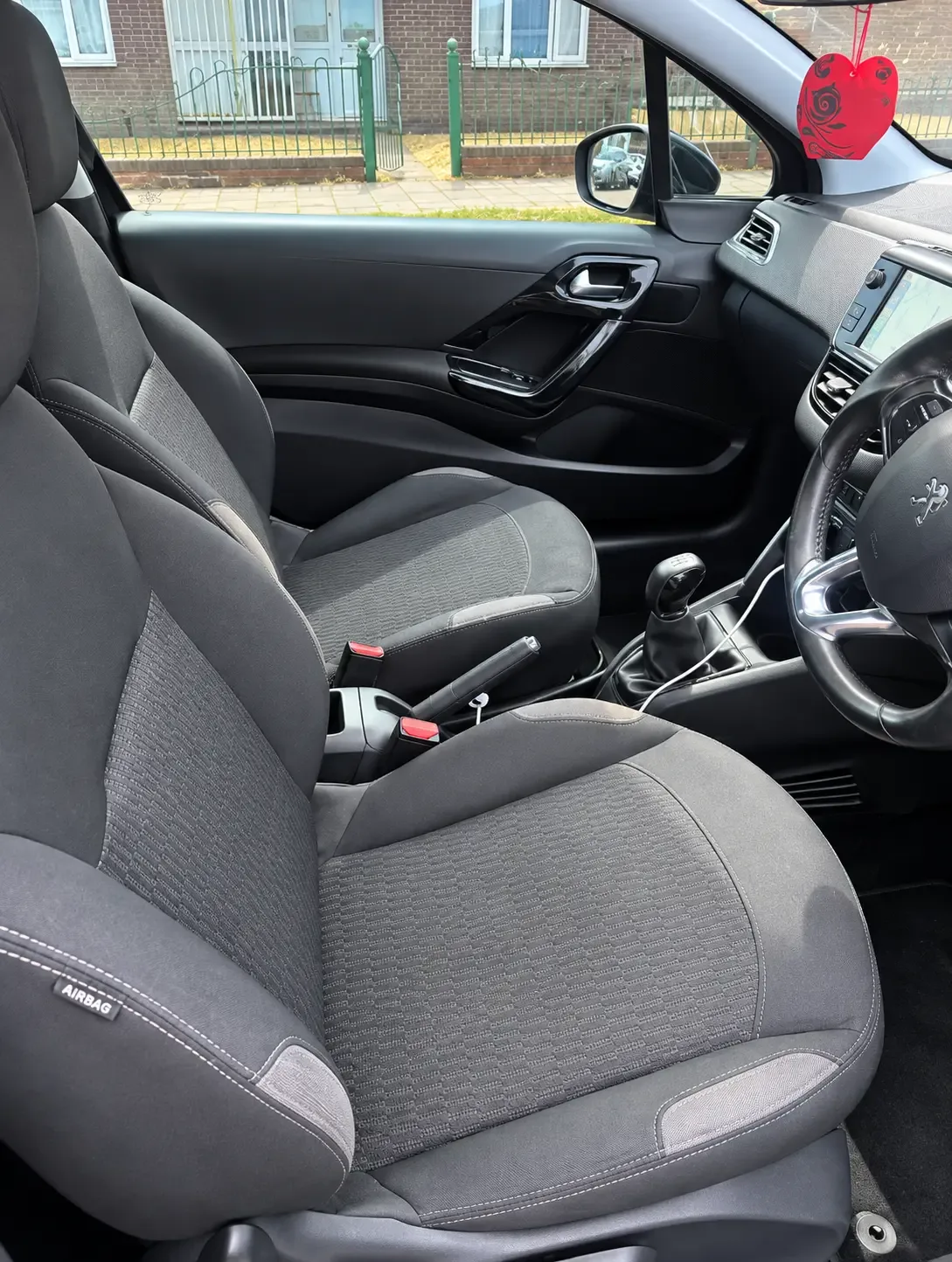 Peugeot 208 interior showing front cloth seats, dashboard and steering wheel